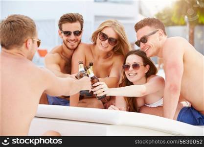 Group Of Young People On Holiday Relaxing By Swimming Pool