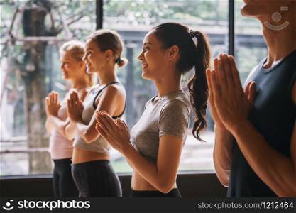 Group of young people practicing yoga In the prayer position at gym, Concept of relaxation and meditation