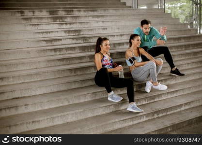 Group of young people resting during training with bottle of water in urban environment