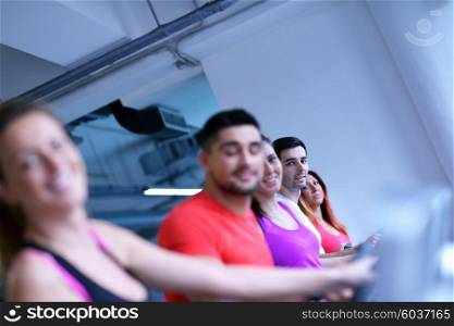 group of young people running on treadmills in modern sport gym