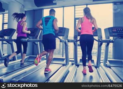 group of young people running on treadmills in modern sport gym. Group of people running on treadmills