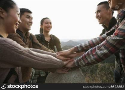 Group of young people smiling and holding hands together on the stone