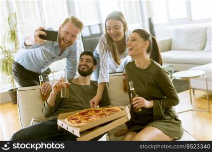 Group of young people taking selfie with mobile phone on the pizza party in the room