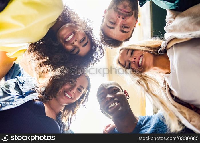 Group of young people together outdoors in urban background. Men and women looking down