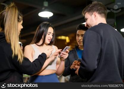 Group of young people using and looking at mobile phone together. High quality photo. Group of young people using and looking at mobile phone together