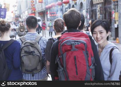 Group of young people walking down street, woman looking over shoulder.