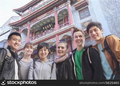 Group of young people with Chinese architecture in background, portrait.