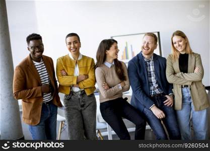Group of young positive businesspeople standing together in the office