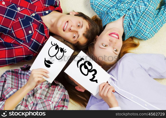 Group of young smiling people lying on floor in circle with phone symbols