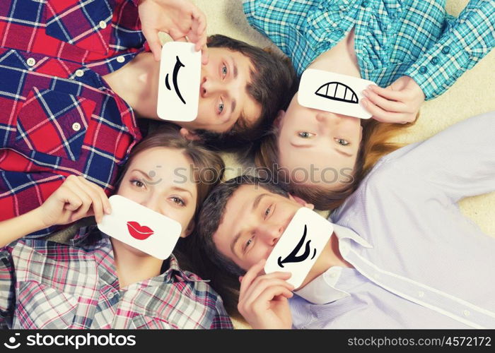 Group of young smiling people lying on floor in circle with phone symbols