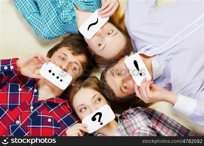 Group of young smiling people lying on floor in circle with phone symbols