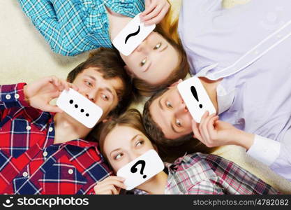 Group of young smiling people lying on floor in circle with phone symbols