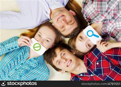 Group of young smiling people lying on floor in circle with phone symbols