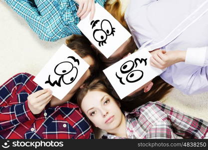 Group of young smiling people lying on floor in circle with phone symbols