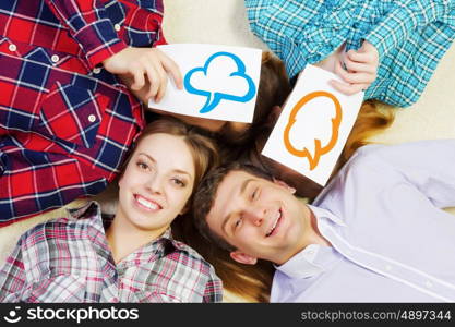 Group of young smiling people lying on floor in circle with phone symbols