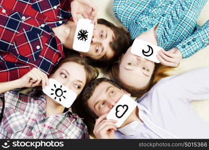 Group of young smiling people lying on floor in circle with phone symbols