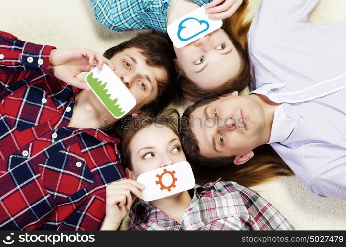 Group of young smiling people lying on floor in circle with phone symbols