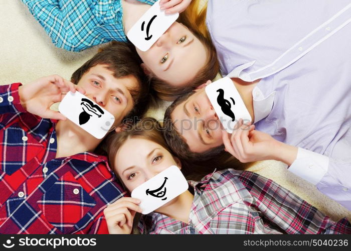 Group of young smiling people lying on floor in circle with phone symbols