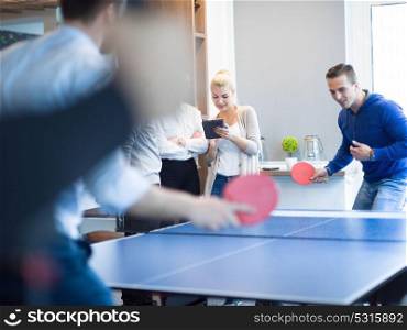 group of young startup business people playing ping pong tennis at modern creative office