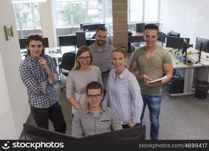 group of young startup business people standing as team at office desk while working on everyday job