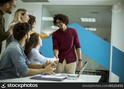 Group of young startup coworkers interacting around a table and handshaking in the office