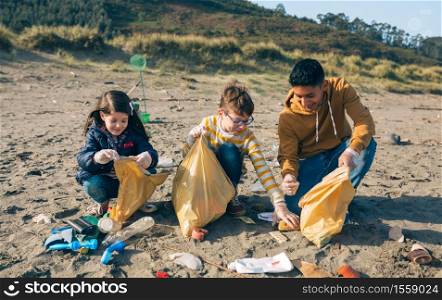 Group of young volunteers picking up trash on the beach. Young volunteers cleaning the beach