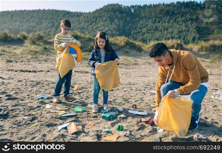 Group of young volunteers picking up trash on the beach. Young volunteers cleaning the beach