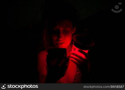 Group of young women having fun at a lakeside party at night with a red light