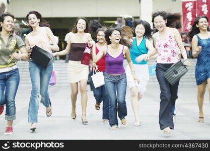Group of young women running with shopping bags