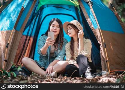 Group of young women sitting at front of c&ing tent in nature park have video call on smartphone with happiness together