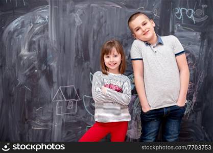 group portrait of happy childrens boy and little girl standing in front of black chalkboard