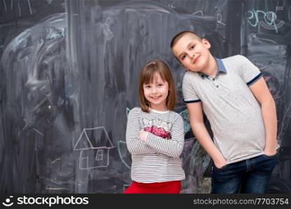group portrait of happy childrens boy and little girl standing in front of black chalkboard