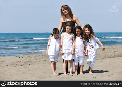 group portrait of happy childrens with young female teacher on beach