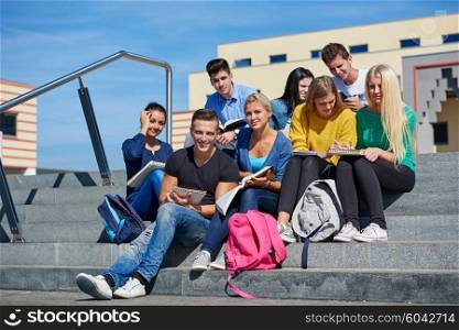 Group portrait of happy students outside in front of school sitting on steps have fun