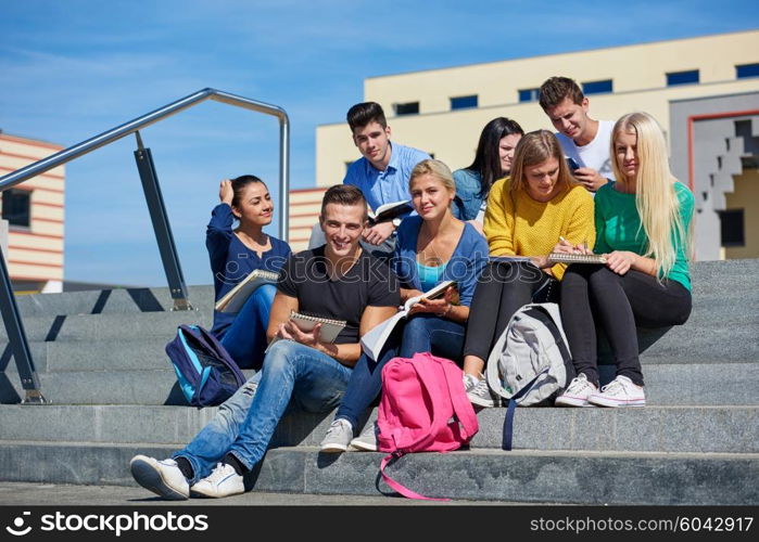 Group portrait of happy students outside in front of school sitting on steps have fun