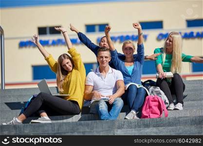 Group portrait of happy students outside in front of school sitting on steps have fun