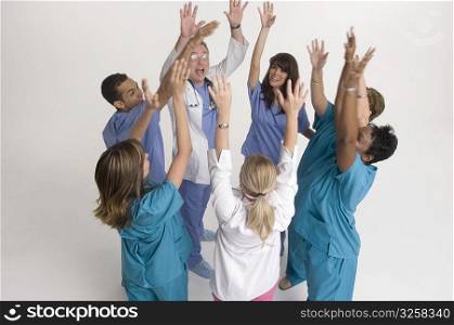 Group portrait of nurses and doctors cheering in circle
