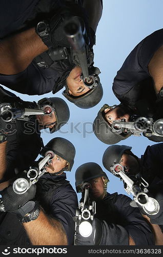 Group portrait of Swat officers standing in circle, aiming guns