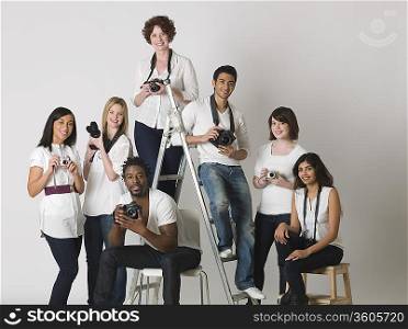 Group portrait of young photographers sitting on ladder and chairs