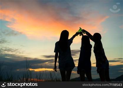 group teen women asian drinking beer from bottles in the midst of nature. While standing back when the sunset.