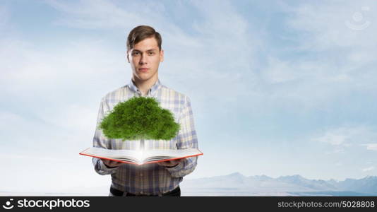 Grow your knowledge. Young man with book in hands and green tree on pages