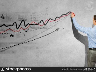 Growing graph. Back view of businessman drawing graphs on wall