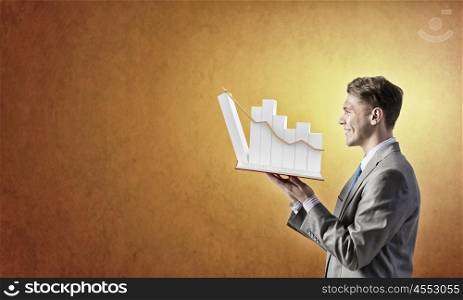 Growing graph . Businessman holding in hands opened book with graphs