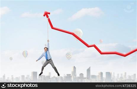 Growing graph. Young businessman hanging on increasing red graph