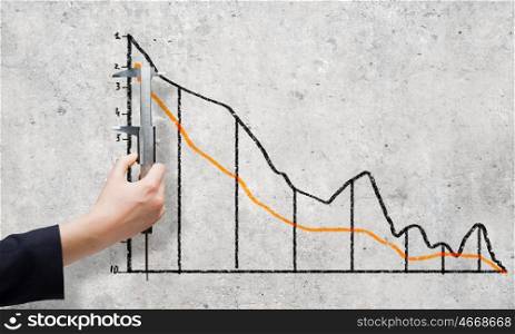 Growth concept. Close up of female hand measuring graph with ruler