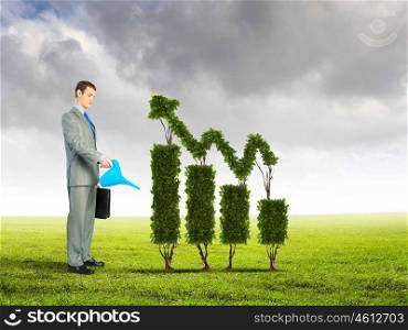 Growth concept. Image of businessman watering plant shaped like arrow