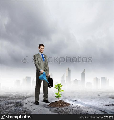 Growth concept. Image of businessman watering sprout with can