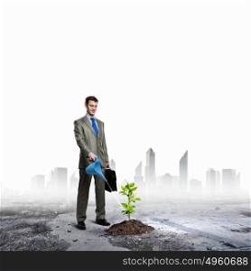 Growth concept. Image of businessman watering sprout with can