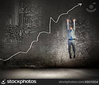 Growth concept. Image of young businessman jumping above graph