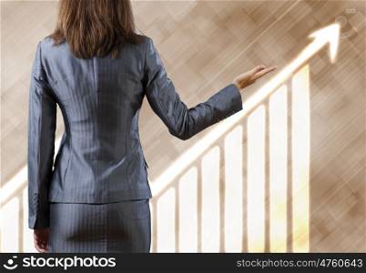 Growth concept. Rear view of businesswoman pointing at growth graph